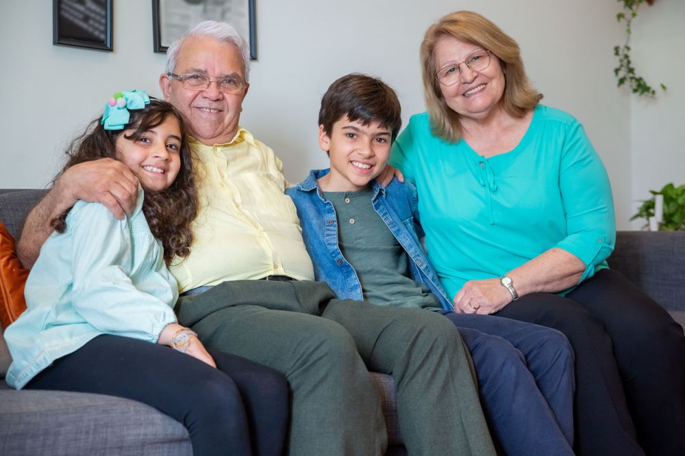 Grandparents sitting on a couch with their two grandchildren, everyone smiling